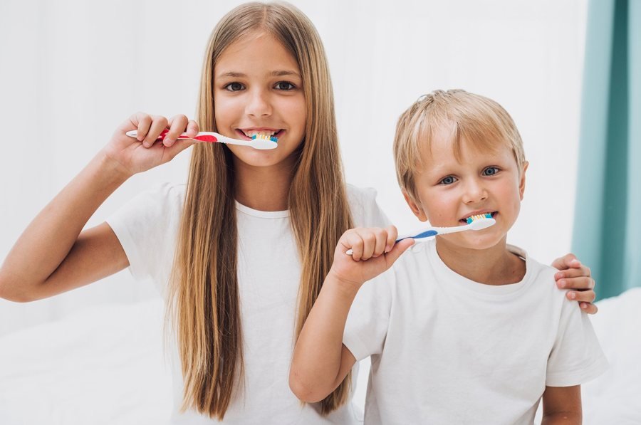 Duas crianças a escovar os dentes